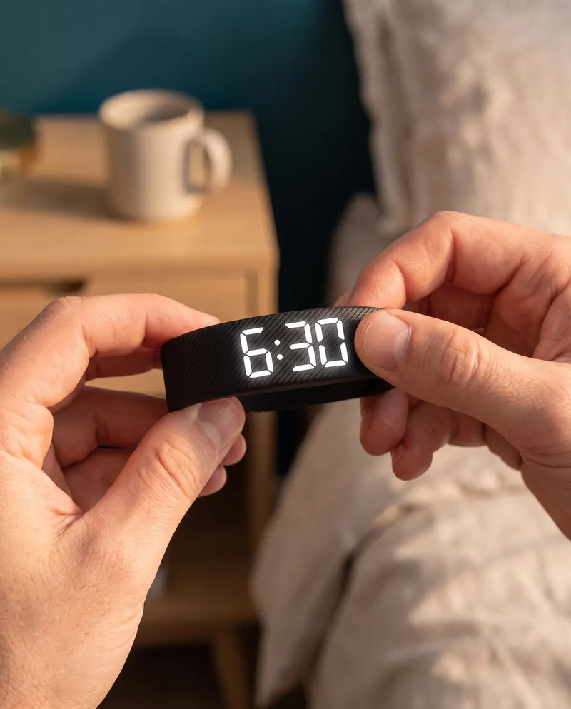 Two hands holding the Touchwake band, its display reading 6:30